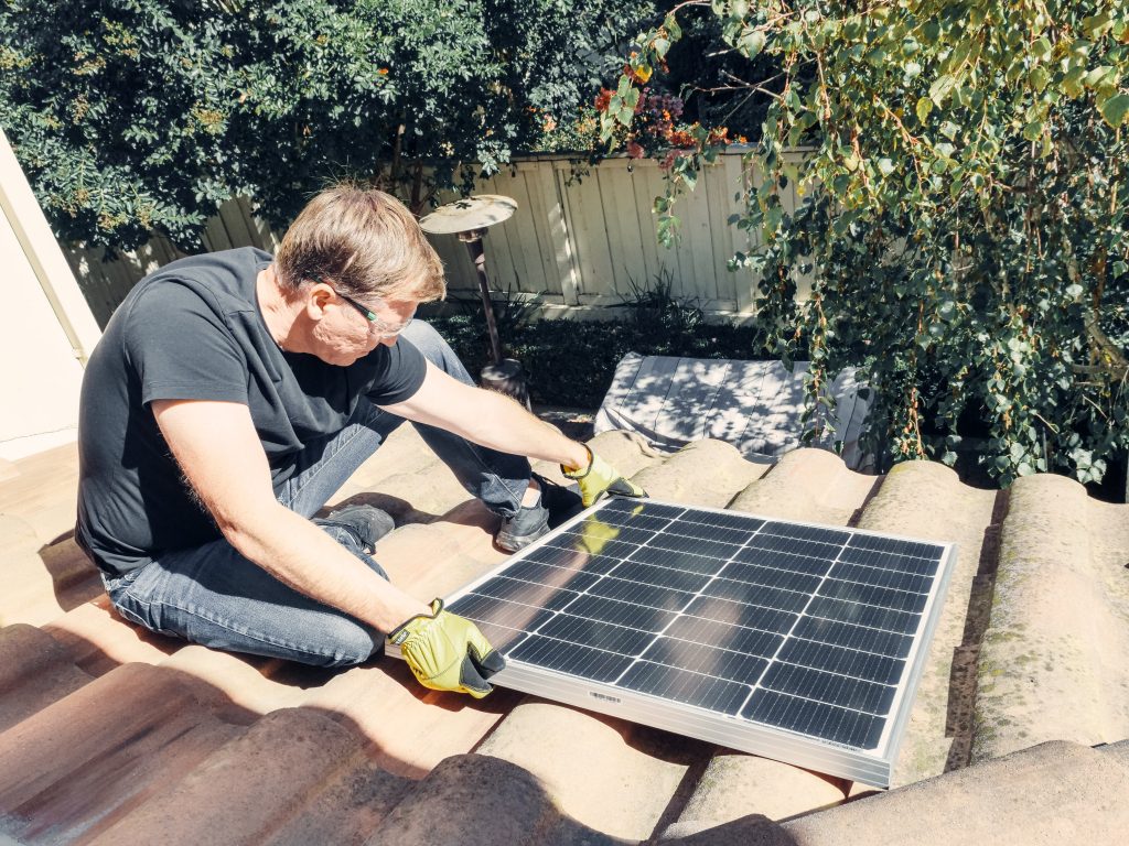 kit solaire autoconsommation 1000W homme sur son toit qui pose un panneau solaire